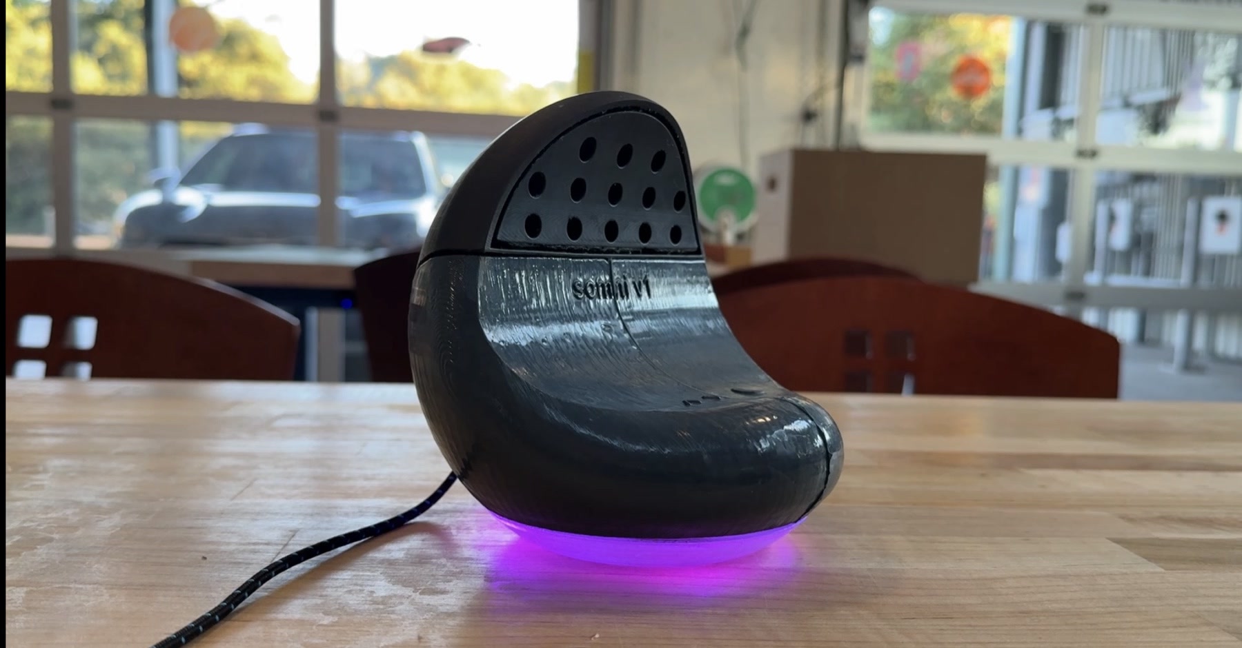 Somni V1 device on a workshop table with violet LED ring glowing